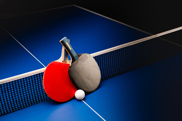 Ping pong rackets and balls on a blue table with net. - obrazy, fototapety, plakaty