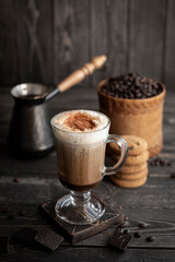 Aromatic coffee with cream and chocolate on dark rustic background
