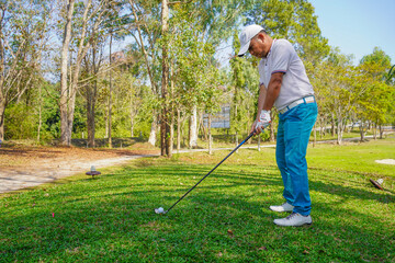 Golfer playing golf in the evening golf course, on sun set evening time. Man playing golf on a golf course in the sun.