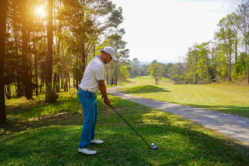 Golfer playing golf in the evening golf course, on sun set evening time. Man playing golf on a golf course in the sun.