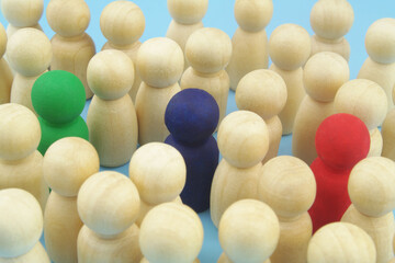Uniqueness, talent search, individuality and recruitment concept. Crowd of wooden people figures, few figures colored.