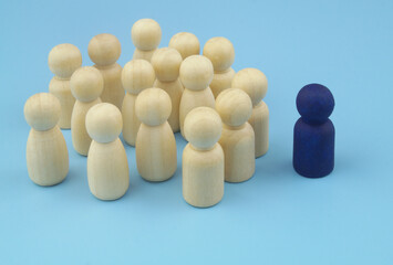 Group of wooden people figures with colored leader on blue background. Concept of business leadership for team, and management.