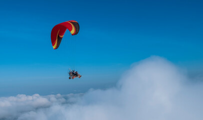 paragliding in the white puffy cloud and blue sky. Freedom and challenging concept.