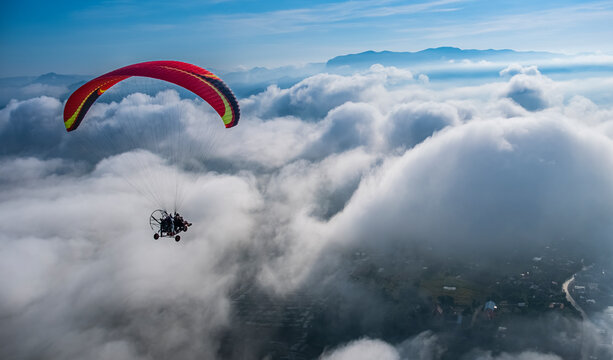 Paramotor is flying in the sky in the morning among white puffy cloud. Evtreme sport concept. Freedom concept.