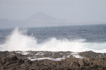 Wave breaking against the shore and Galdar Mountain. El Confital. La Isleta. Las Palmas de Gran Canaria. Gran Canaria. Canary Islands. Spain.