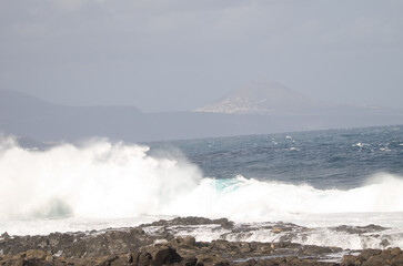 Wave breaking against the shore and Galdar Mountain. El Confital. La Isleta. Las Palmas de Gran Canaria. Gran Canaria. Canary Islands. Spain.