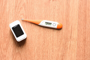 Pulse oximeter and digital thermometer on wooden background - 493599741