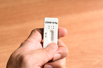 Slowly checking ATK Antigen Rapid Test Kit with Positive Result Detected of Covid-19 Virus on hand	 - 493600103