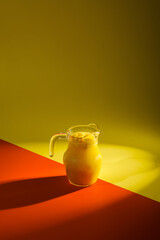 Fresh mango smoothie in the glass on orange and yellow background. summer drink.