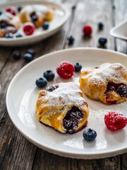 Puff pastry with raspberries and blueberries on wooden table
