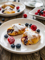 Puff pastry with raspberries and blueberries on wooden table
