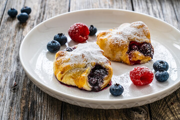 Puff pastry with raspberries and blueberries on wooden table

