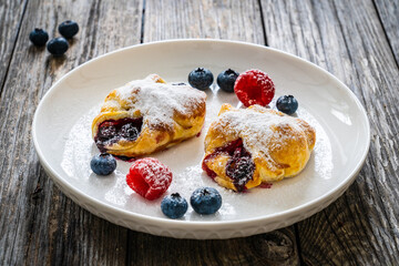 Puff pastry with raspberries and blueberries on wooden table
