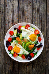 Salmon salad - smoked salmon, sunny side eggs,  avocado and fresh vegetables on wooden table
