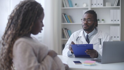 Obraz premium Gynecologist listening, writing down pregnant woman's complaints during exam