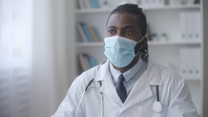 General practitioner in protective face mask carefully listening to patient complains