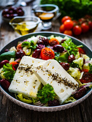 Fresh Greek salad - feta cheese, cherry tomatoes, cucumber and onion on wooden table
