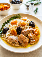 Chicken nuggets with rice, plums and apricots on white table
