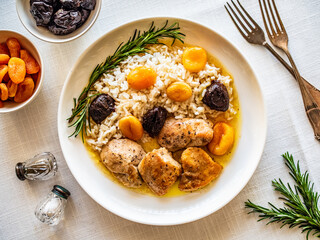 Chicken nuggets with rice, plums and apricots on white table
