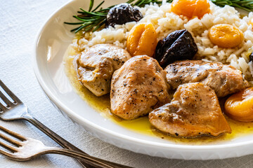 Chicken nuggets with rice, plums and apricots on white table
