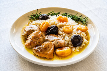 Chicken nuggets with rice, plums and apricots on white table
