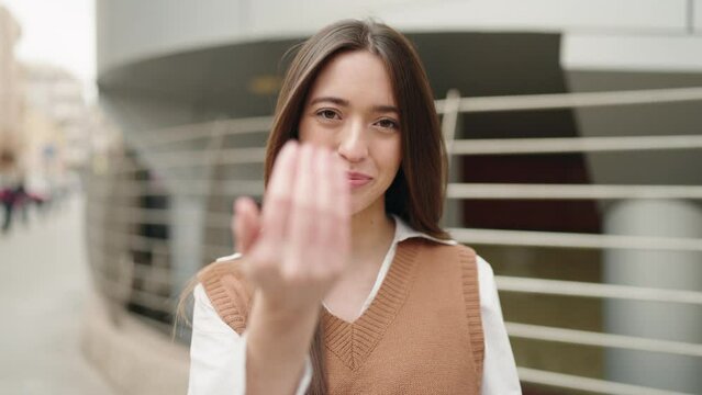 Young hispanic woman smiling confident doing coming gesture at street