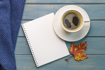 Composition with autumn leaves, blank notebooks, a cup of coffee on a blue wooden table
