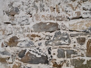 Close up of old barn facade. Stone wall with crumbling white plaster.