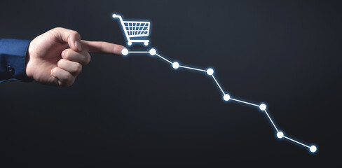 Male hand touching down graph with a shopping cart. Sales decline