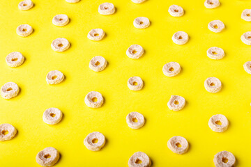 Fototapeta premium dry breakfasts in the form of rings on a yellow background, pattern