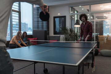 Two young start up business man playing ping pong tennis at modern creative office space people...