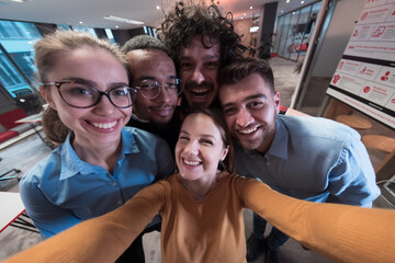 Group of business people during break from the work taking selfie picture while enjoying free time in relaxation area at modern open plan startup office. Selective focus 