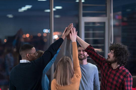 Overjoyed young multiethnic businesspeople have fun celebrate shared business success or victory in office. Smiling multiracial diverse employees feel excited win get good results. Teamwork concept.