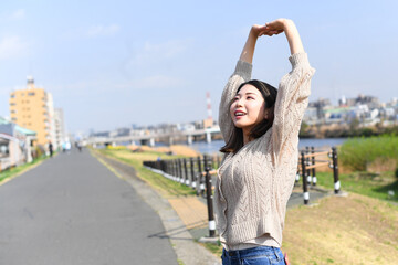 屋外で伸びをするリフレッシュ中の若いアジア人女性