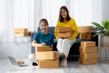 Two owners of an online store on the website are preparing parcels to send to customers following orders from the web page, they check the information and prepare for delivery to the customers.