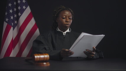 Black judge reading legal papers during proceeding, American justice system
