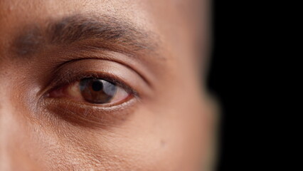 Black man opening eye on dark background, eyesight examination, optometry