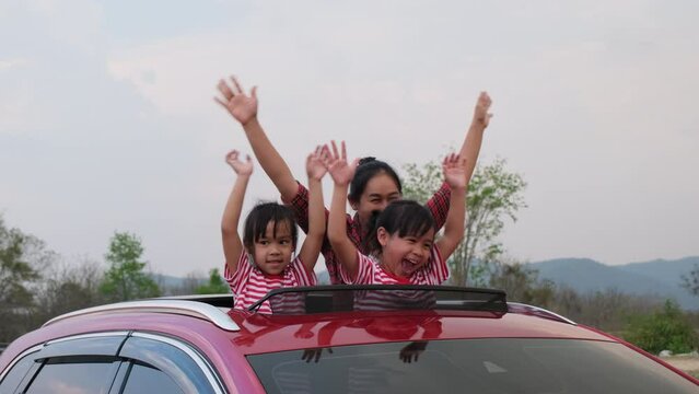Happy family enjoying road trip on summer vacation. Mother and child enjoying nature along the way in the car on sunroof. Holiday and travel family concept.