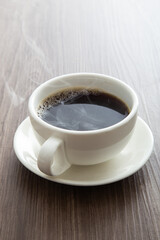 Hot coffee cup with smoke on the wooden background