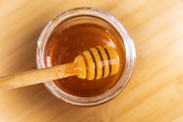 Wooden ladle with dripping honey close up, beekeeping products based on the concept of organic...
