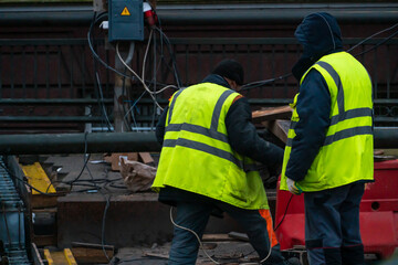 Employees of the road service in special yellow vests perform work on the repair of the roadway. Restoration of the deformation seam of the automobile bridge.