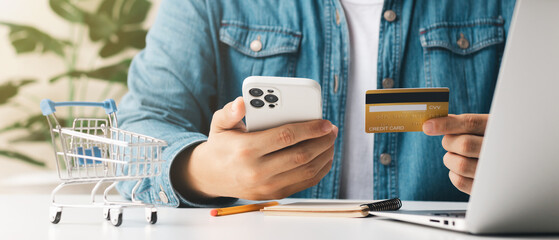 Businessman hand holding credit card with using smartphone for online shopping while making orders...