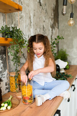 The girl is in the kitchen. Holds pasta. 