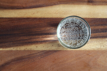 A transparent glass with soda stands on a wooden table. refreshing drink