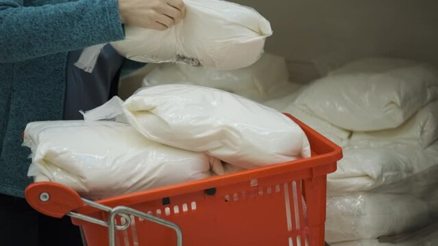 Woman Putting Sacks of Granulated Sugar in Grocery Cart in a Supermarket or Warehouse, Wholesale Trade. Hoarding, Economic Crisis and Food Shortage
