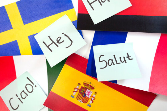 The word "hello" in different foreign languages on stickers against the background of flags of different countries