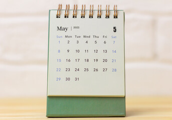 Desktop calendar for May 2022 on a wooden table.