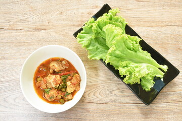 spicy fried pork bone and tendon with coconut milk curry in bowl with lettuce on plate