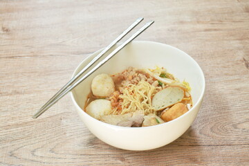 egg yellow noodles noodles topping slice boiled pork and ball in spicy tom yum soup on bowl