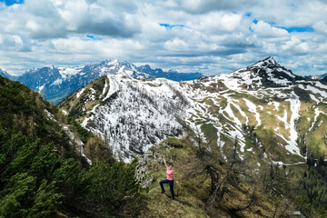 Fototapeta na wymiar Hiker woman with backpack at summit of Hahnkogel (Klek) with scenic view on mountain peaks in Karawanks and Julian Alps, Carinthia, Austria. Border with Slovenia. Triglav National Park. Goal seeking